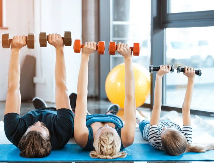 Happy,Family,Exercising,With,Dumbbells,At,Fitness,Studio